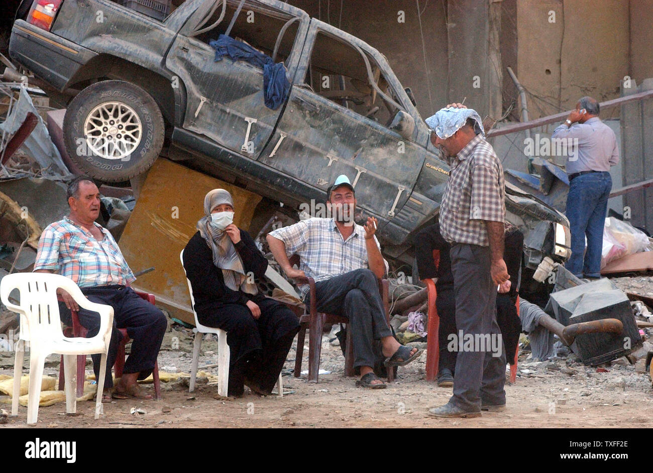 Residents of Beirut's southern suburbs take a break from searching in the rubble of their building for belongings on August 24, 2006. The Hezbollah organization is paying people who have lost property a stipend to relocate until their own home can be rebuilt. (UPI Photo) Stock Photo