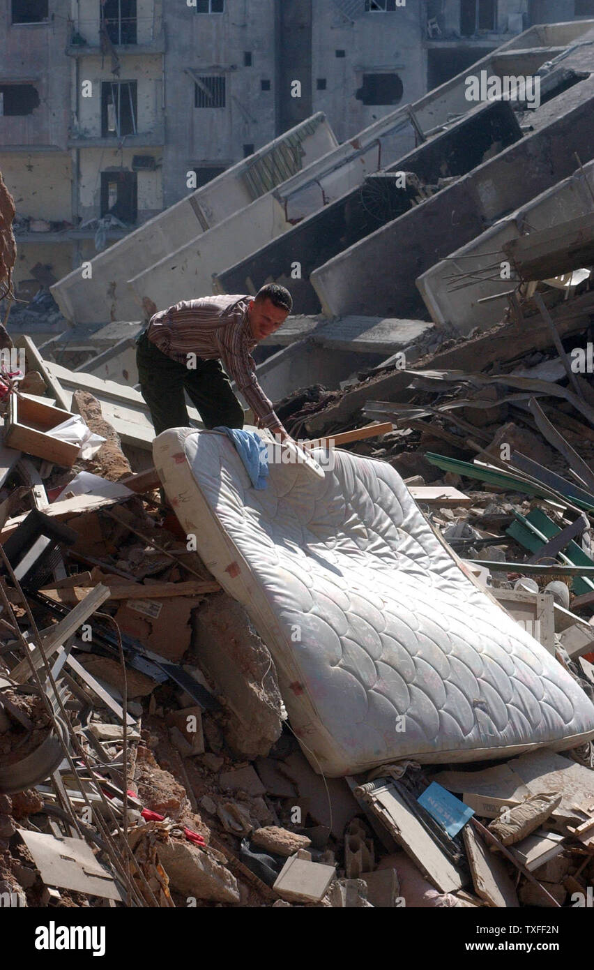 A resident of Beirut's southern suburbs removes a mattress from the rubble his building on August 24, 2006. The Hezbollah organization is paying people who have lost property a stipend to relocate until their own home can be rebuilt. (UPI Photo) Stock Photo