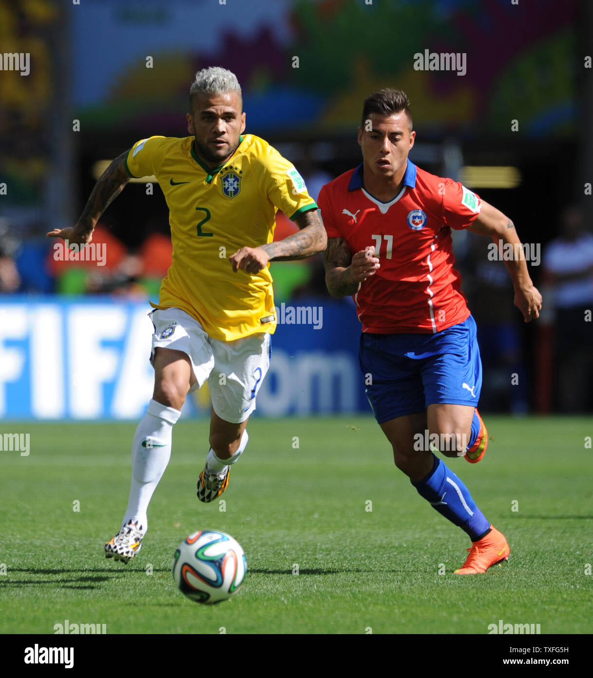 Dani Alves (L) of Brazil is chased by Eduardo Vargas of Chile during the 2014 FIFA World Cup Round of 16 match at the Estadio Mineirao in Belo Horizonte, Brazil on June 28, 2014. UPI/Chris Brunskill Stock Photo