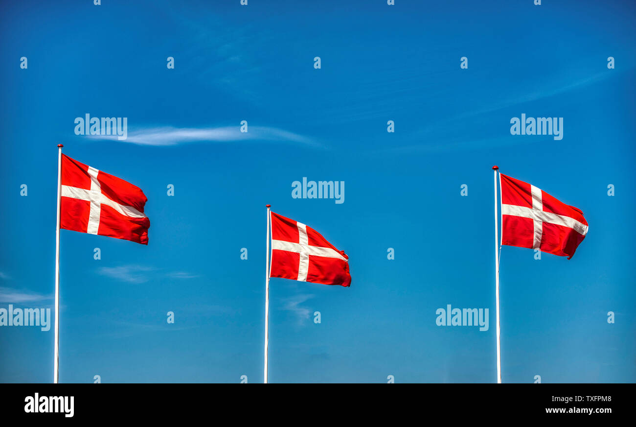 Three Danish flags against a blue sky Stock Photo