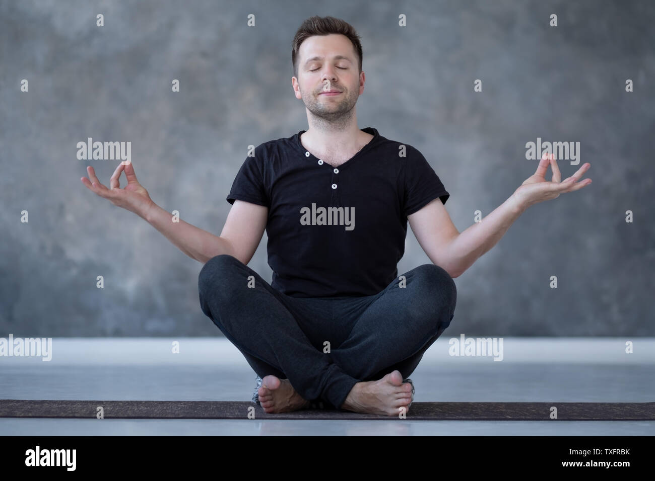 Yoga male beginner practicing yoga sitting in pose and meditates Stock