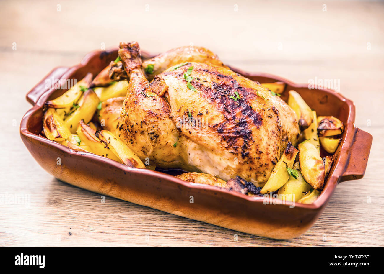 Roasted whole chicken with potatoes in baking dish. Tasty food at home on the kitchen counter