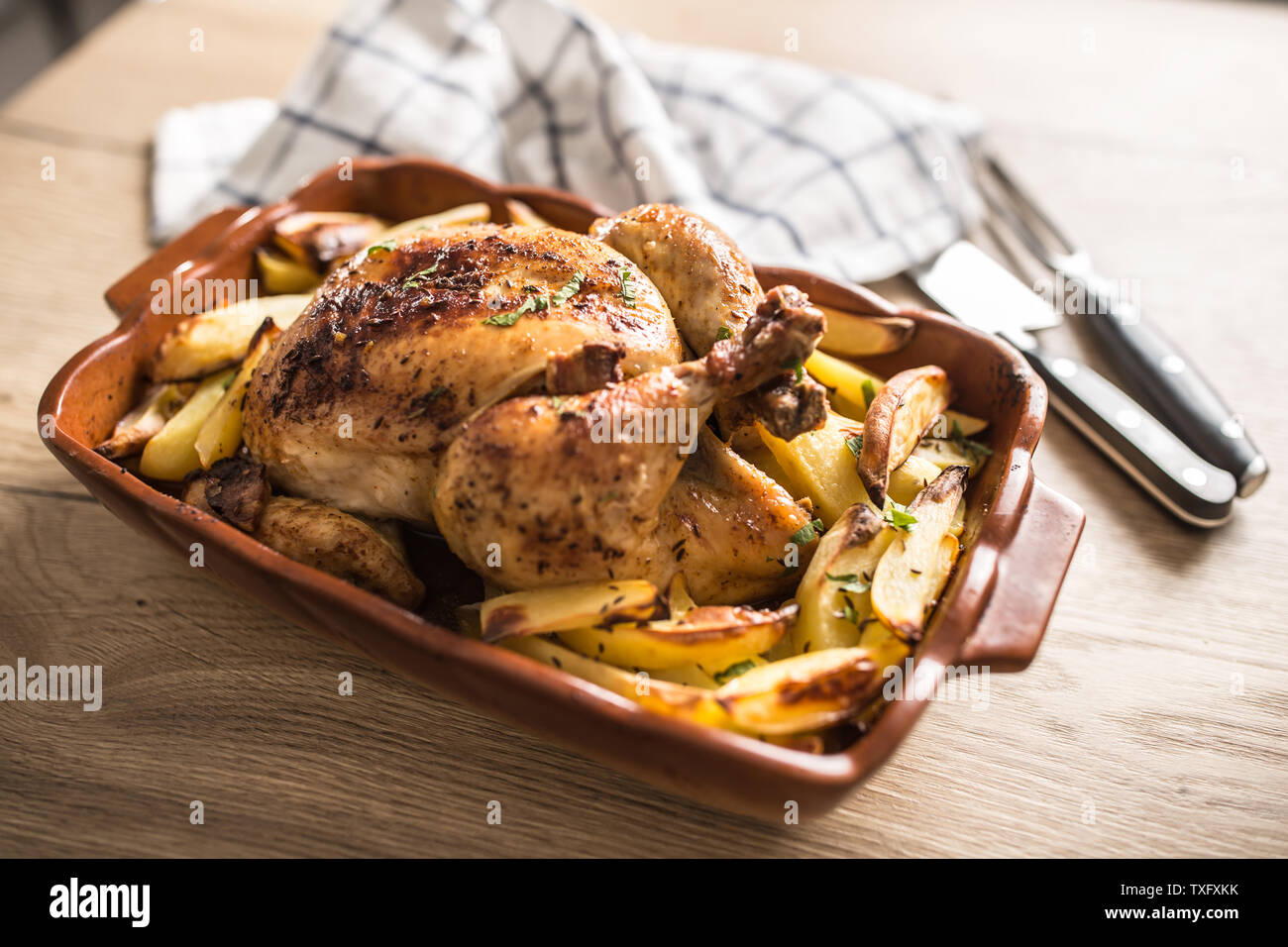 Roasted whole chicken with potatoes in baking dish. Tasty food a Stock Photo
