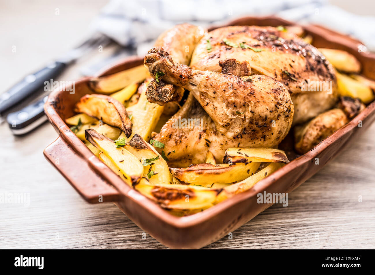 Roasted whole chicken with potatoes in baking dish. Tasty food at home on the kitchen counter Stock Photo