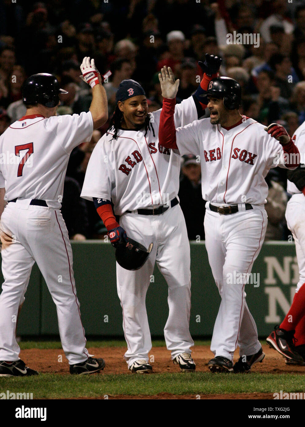 Boston Red Sox third baseman Mike Lowell (R) is patted on the head by left  fielder Manny Ramirez (C) and given a high five by right fielder J.D. Drew  after Lowell hit