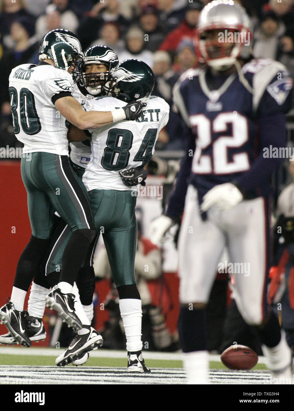 Members of the Philadelphia Eagles Kevin Curtis (80) and Hank Baskett (84) give a hug to teammate Greg Lewis (C) after Lewis scored in the second quarter against the New England Patriots at Gillette Stadium in Foxboro, Massachusetts on November 25, 2007. Walking off the field is Patriots cornerback Asante Samel (22). (UPI Photo/Matthew Healey) Stock Photo