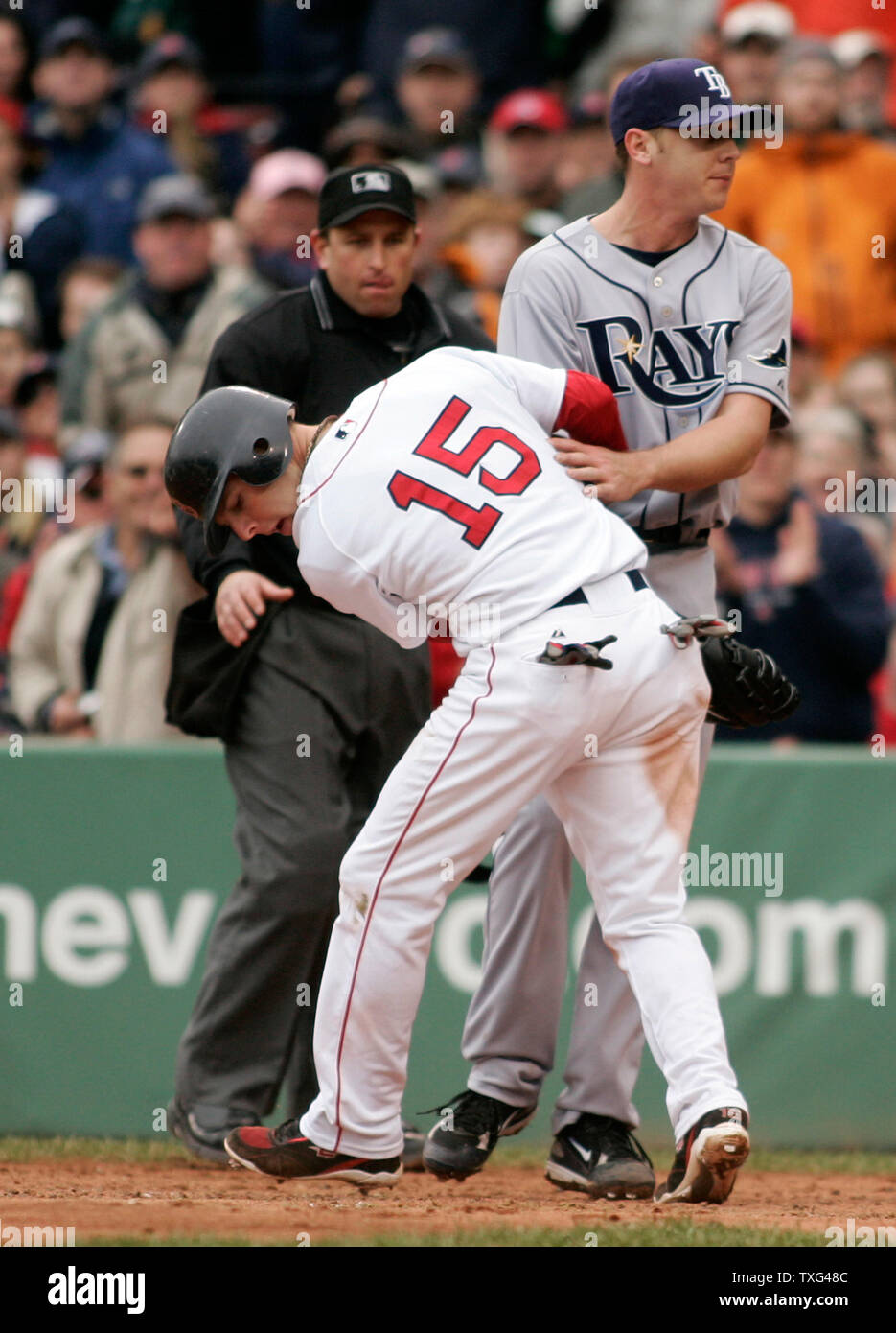 Boston Red Sox base runner Dustin Pedroia (L) bumps into Tampa Bay Rays pitcher Scott Kazmir to score on a wild pitch in the third inning at Fenway Park in Boston, Massachusetts on May 4, 2008.  Umpire Chris Guccione looks on in the background. (UPI Photo/Matthew Healey) Stock Photo