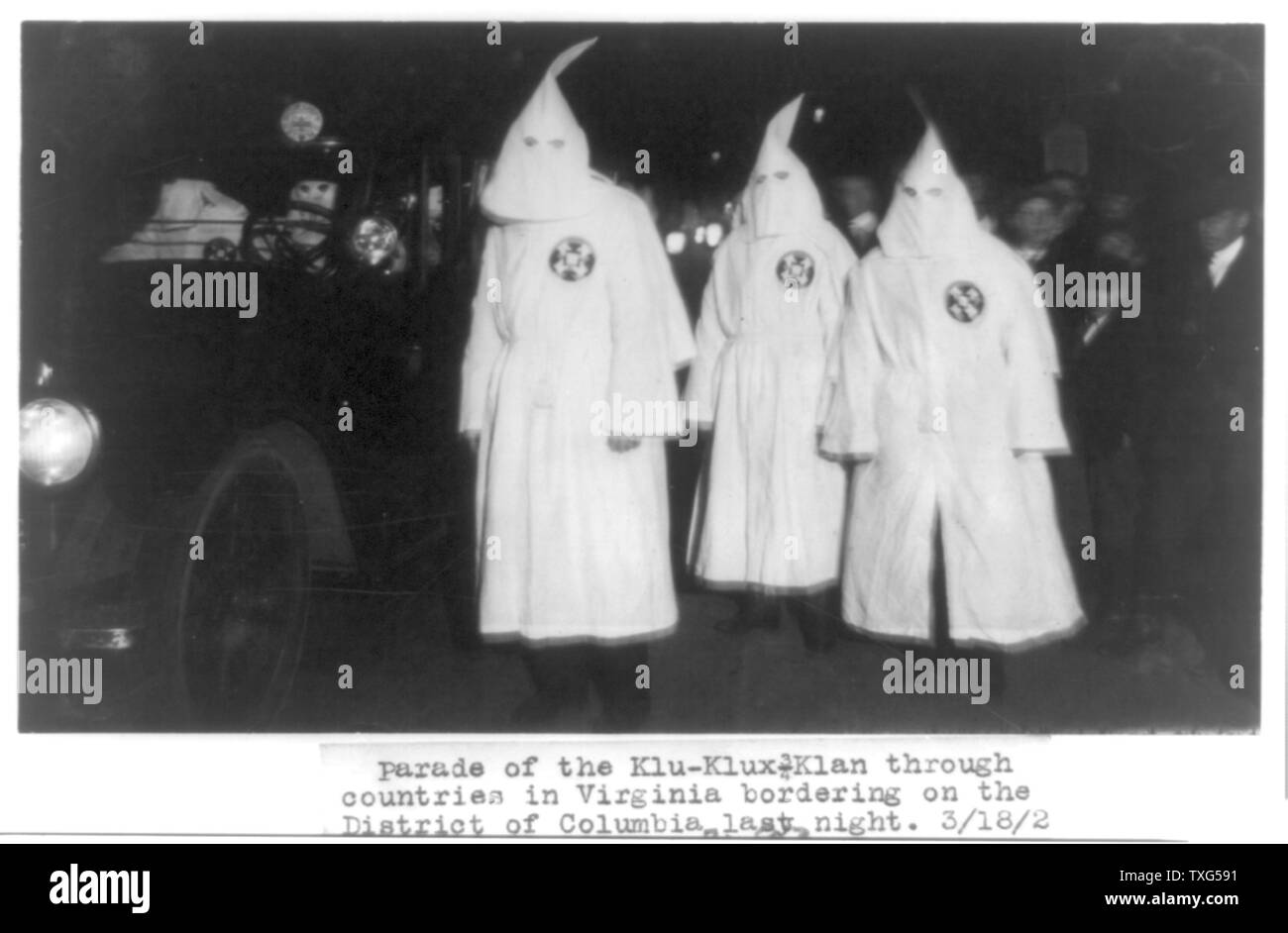 Three members of the Ku Klux Klan in masks and gowns taking part in a night parade Stock Photo