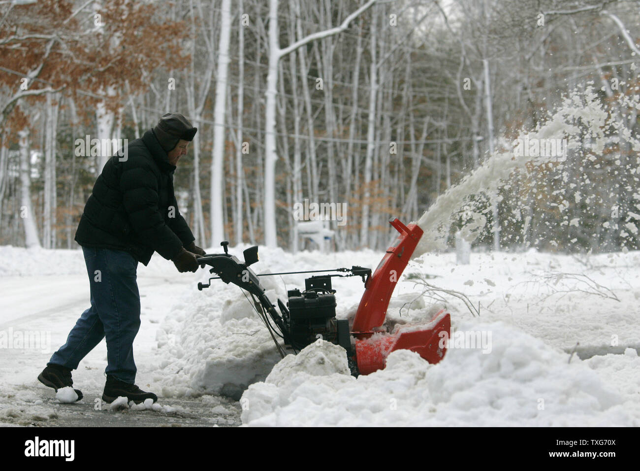 Bob Powers uses a snow blower to clear the edge of his home in Norwell, Massachusetts on