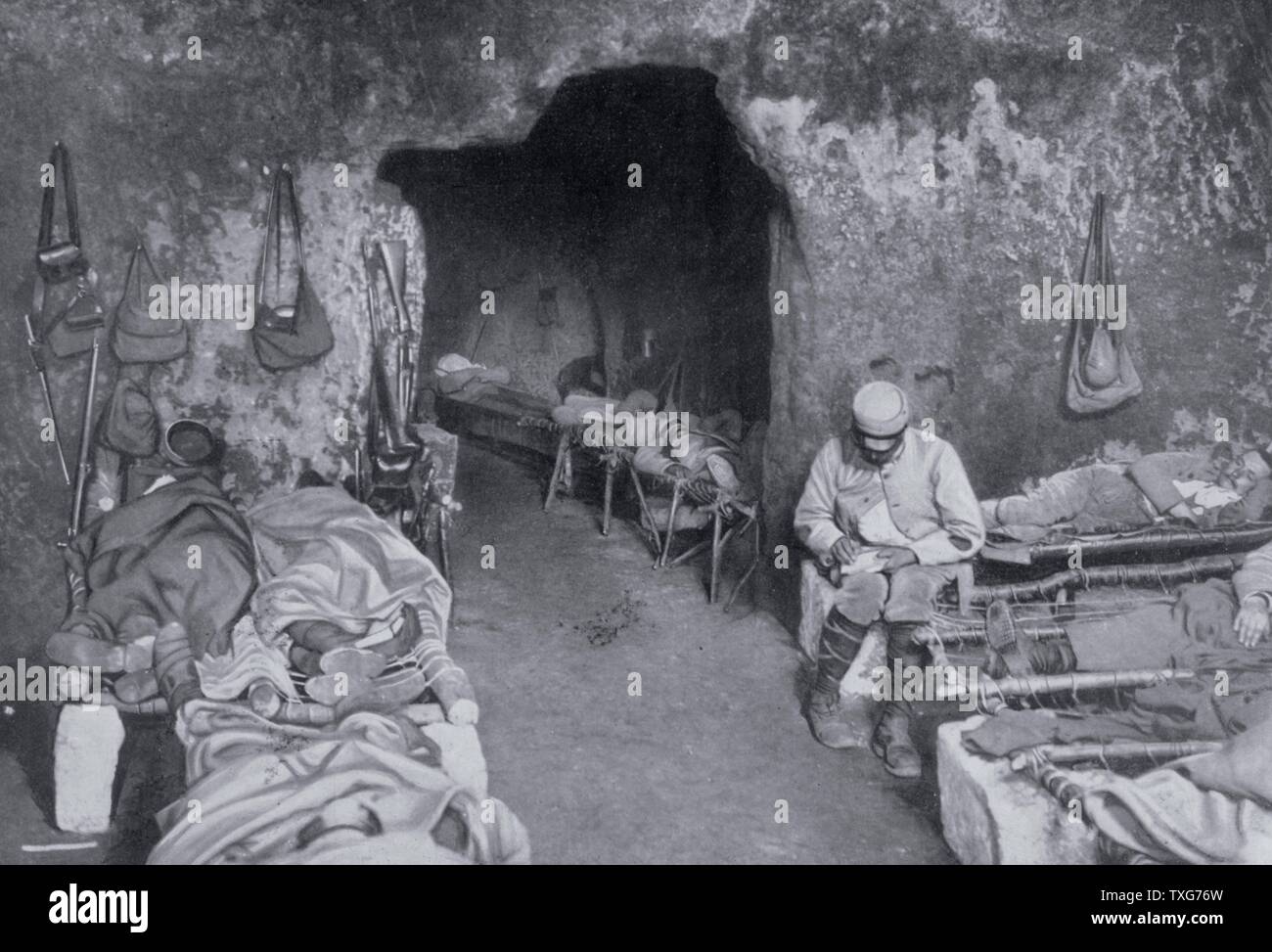 World War I   : French soldiers resting in a grotto in a trench complex. Most are sleeping on improvised beds and one is writing a letter From 'Le Flambeau', Paris Stock Photo