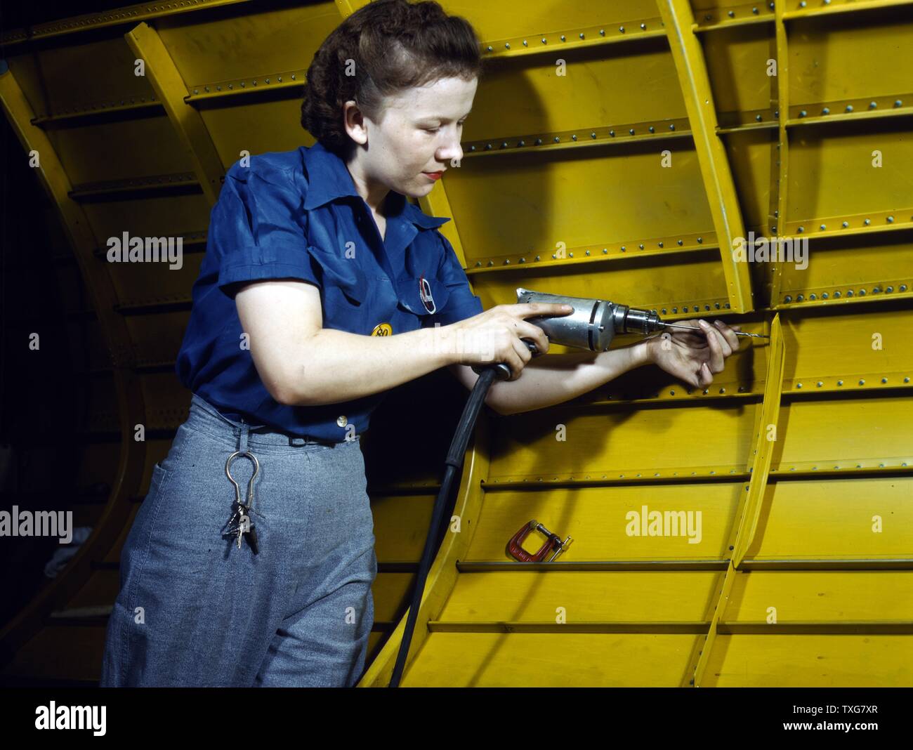 Female aviation worker using a rivet gun on the interior of a USAF