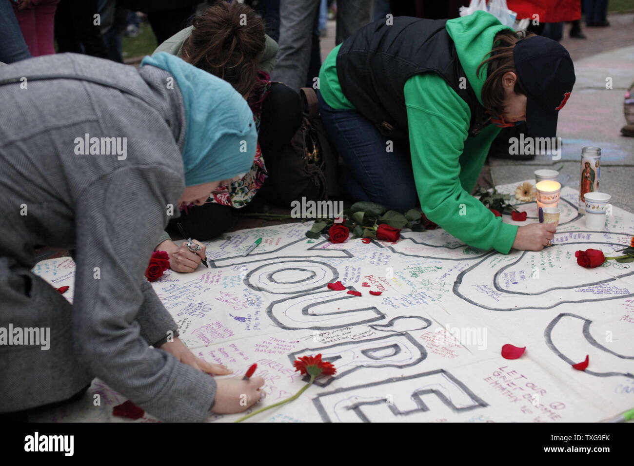 People sign a banner at a candlelight vigil held at Boston Common in Boston, Massachusetts on April 16, 2013.  The vigil is in response to the bombings on Boylston Street near the finish line of the Boston Marathon Monday afternoon killing 3 and injuring 150.    UPI/Matthew Healey Stock Photo