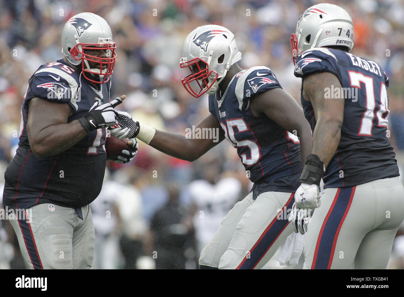 New England Patriots defensive tackle Vince Wilfork (L) is congratulated by  teammates defensive end Chandler Jones (C) and defensive lineman Dominique  Easley after intercepting a pass in the final minutes of the