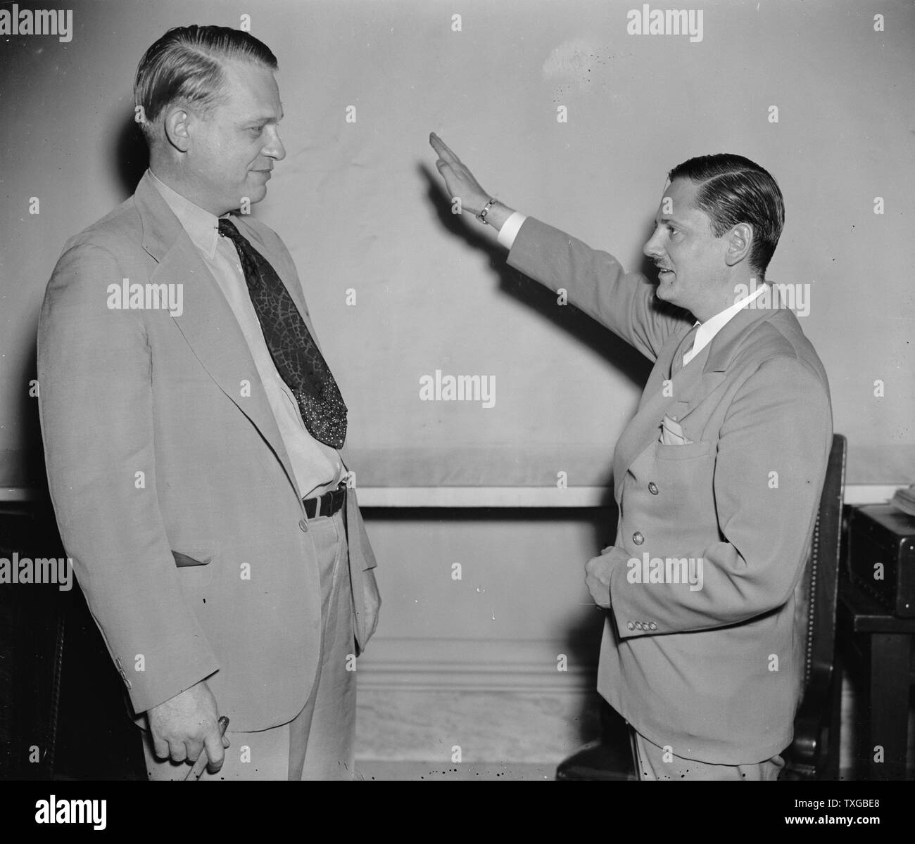 Called as the first witness before the Special House Committee investigating Un-American activities, John Metcalfe, former Chicago reporter but now an investigator for the committee, gives Chairman Martin Dies (right) a Nazi salute before taking the stand. Joining under the name of Helmut Oberwinder, Metcalfe related his experiences as a member of the German-American bund and charged the organization has a secret relationship with the Nazi government in Germany, Stock Photo