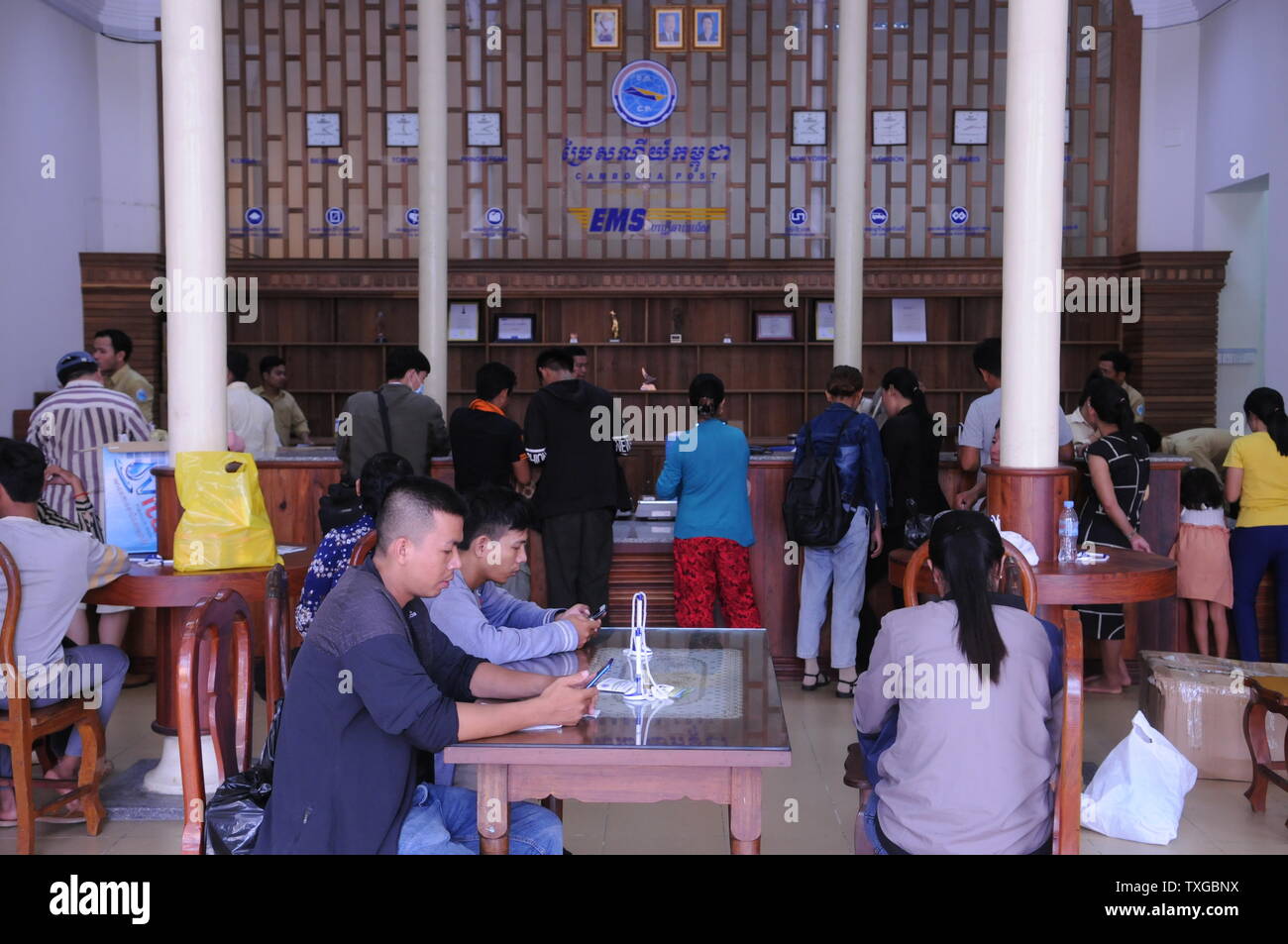 Cambodians mailing at the post office, clocks w/ time zones from around the world on wall, Phnom Penh, Cambodia. credit: Kraig Lieb Stock Photo