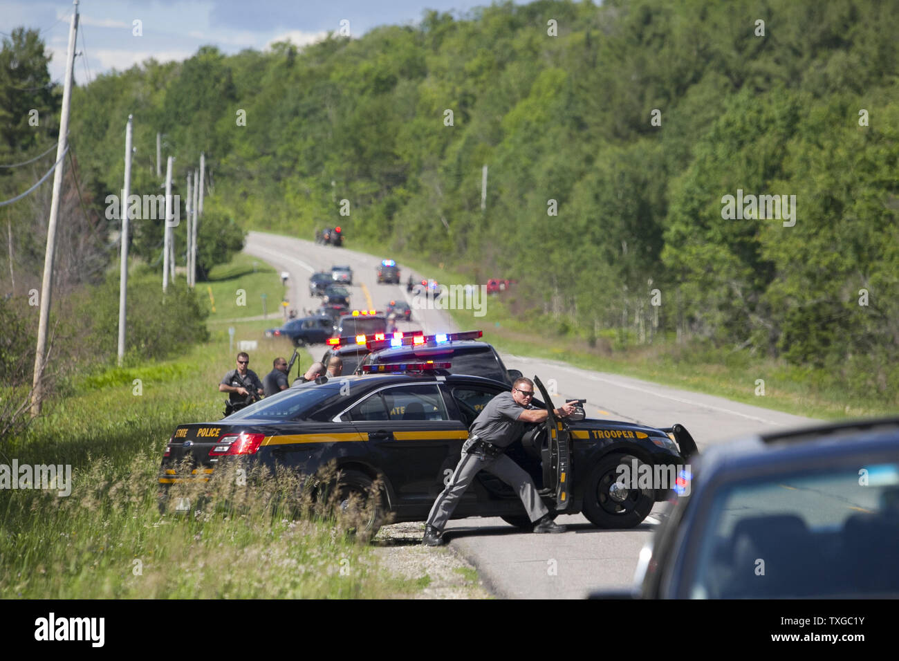 Law enforcement personnel take cover after cornering two escaped prisoners off of Route 30 in Malone, New York on June 26, 2015.  At least one prisoner, Richard Matt, is believed to have been shot dead by law enforcement and second prisoner, David Sweat, may still be on the loose.   Photo by Matthew Healey/UPI Stock Photo