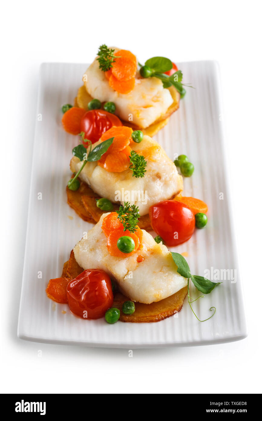 Fish prepared with vegetables on white plate. Isolated on white background. Stock Photo