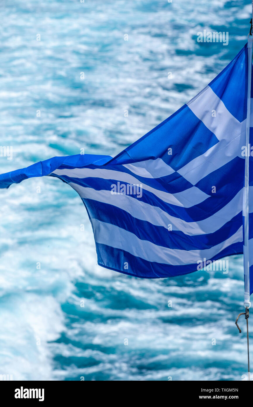 Greek waving flag on a ship while crossing the Aegean sea among the Cyclades islands. Stock Photo