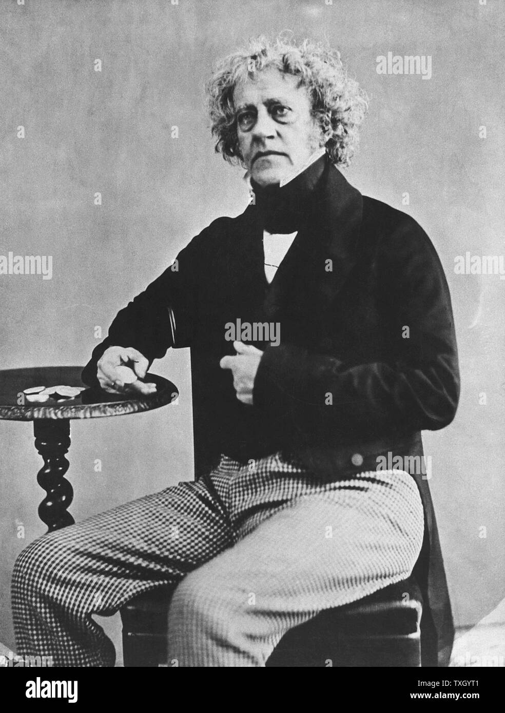 John Frederick Herschel (1792-1871) English astronomer and scientist, from photograph when Master of the Mint (1850-55) showing him holding a florin (2 shilling piece) which was being introduced with the idea of decimalization of the coinage Stock Photo