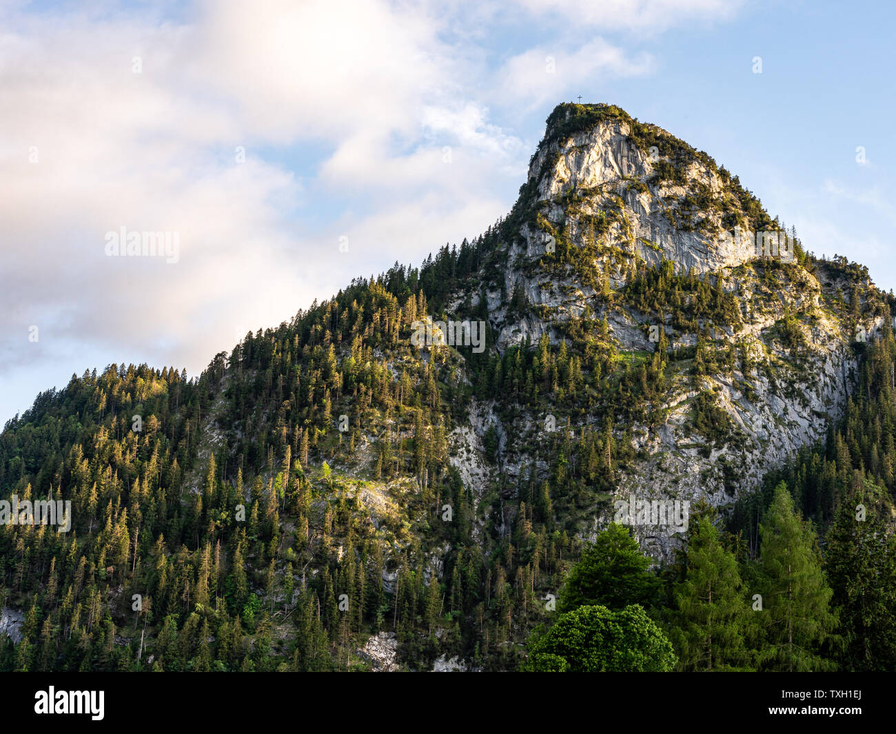 sunlight during sunset illuminates the peak of kofel in Oberammergau