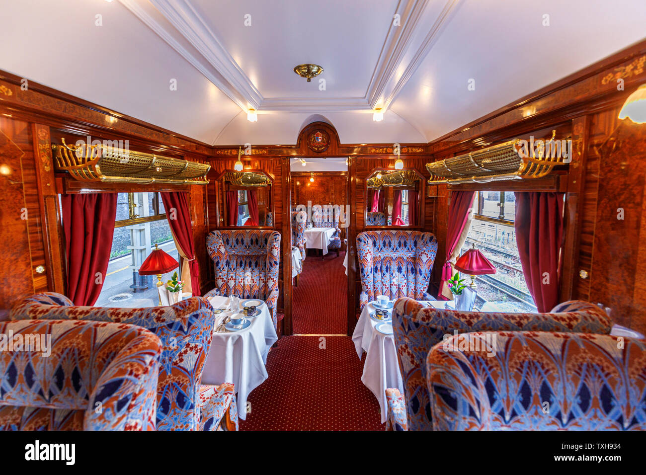 Interior of a panelled dining car Ione with tables set for lunch in the Belmond Venice Simplon Orient Express Stock Photo