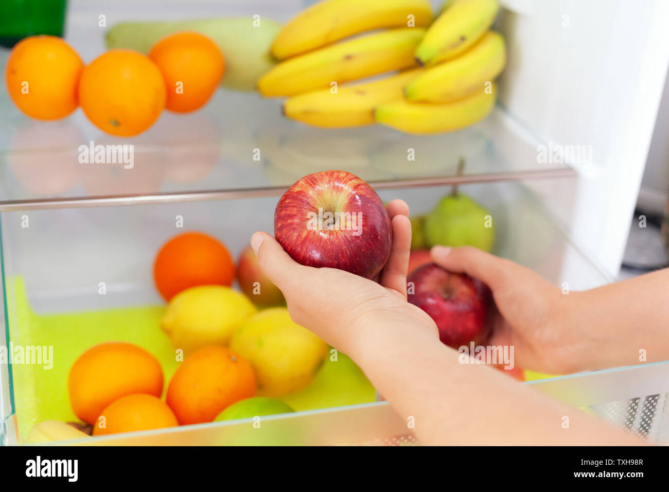 Woman getting red apples from fridge. Close up. Stock Photo