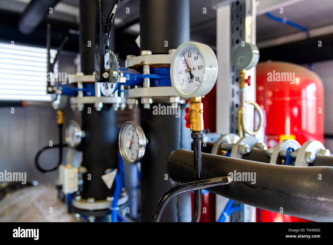 Closeup of manometer, measuring gas pressure. Pipes and valves at industrial plant. Pressure