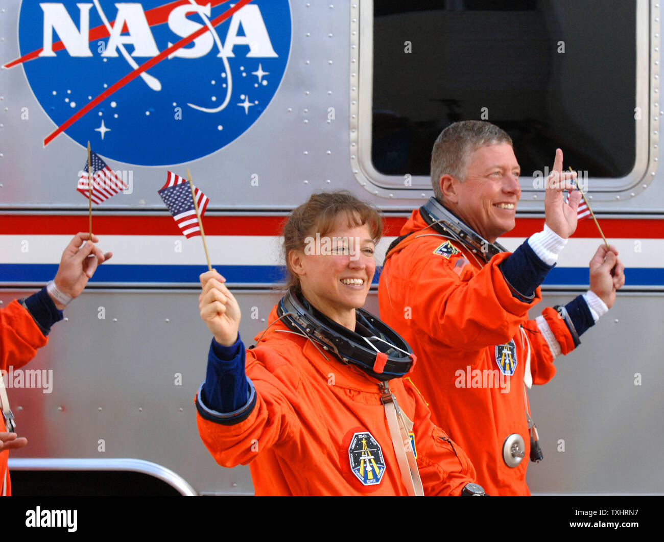 Mission Specialists  Lisa Nowak and Michael Fossum wave American flags as they walk out of the Operations and Checkout Building to board the NASA Astrovan en route to the Space Shuttle Discovery for mission STS-121 at Cape Canaveral, Florida on July 4, 2006. (UPI Photo/Pat Benic) Stock Photo