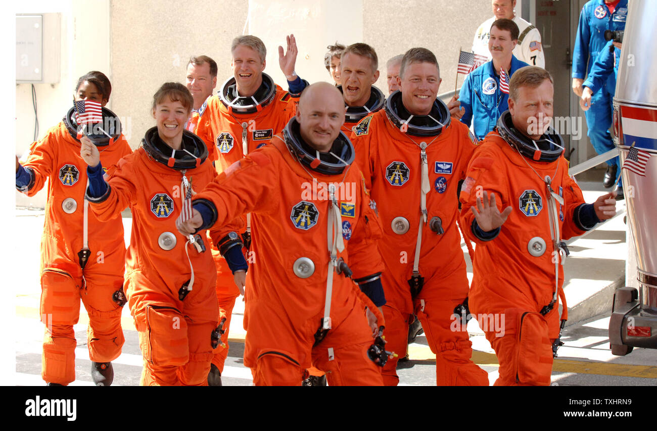 Commander Steven Lindsey (R) and Pilot Mark Kelly (L) wave American Flags as they lead Mission Specialists  Lisa Nowak (2nd Row,L), Michael Fossum (2nd row,R), Stephanie Wilson (3rd Row,L), Piers Sellers, (3rd Row,R), and Thomas Reiter (rear) of Germany, out of the Operations and Checkout Building to board the NASA Astrovan to board the Space Shuttle Discovery for mission STS-121 at Cape Canaveral, Florida on July 4, 2006.  Reiter is waving a German flag for the 4th of July launch. (UPI Photo/Pat Benic) Stock Photo