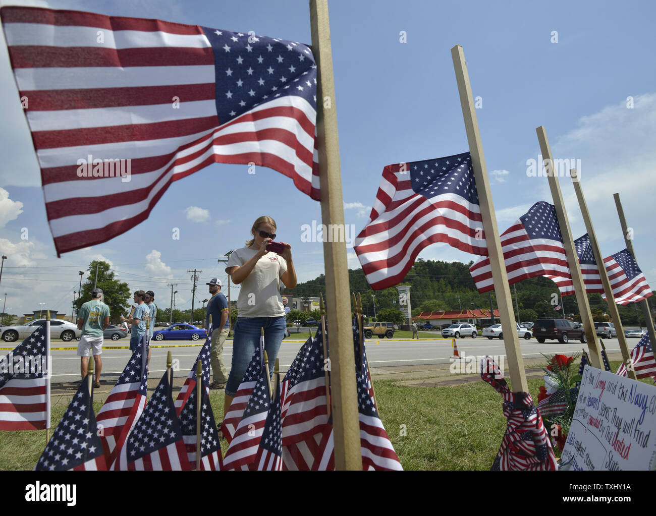 Vicki Baross takes photos in front of a set of flags presented at half-staff at a make shift memorial at the US Navy Operational Support Center & Marine Corps Reserve Center in Chattanooga, Tennessee on July 20, 2015 . The shootings at two different locations left five US Marines and the gunman Mohammod Youssuf Abdulazeez dead. Photo by Billy Weeks/UPI Stock Photo