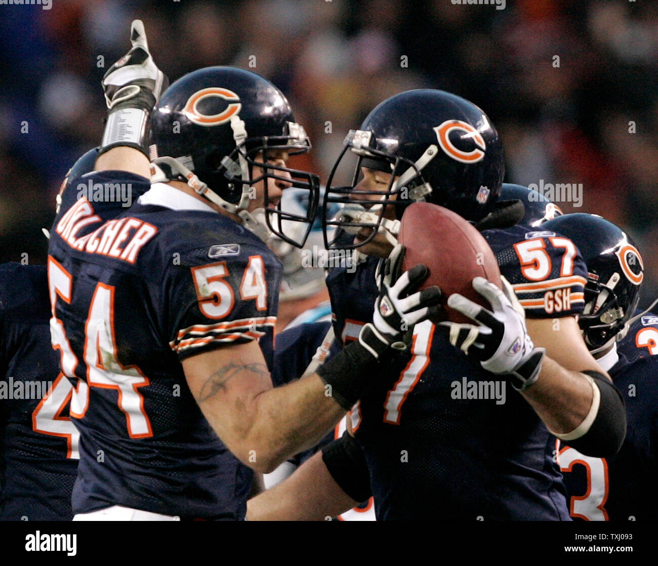 Chicago Bears linebacker Brian Urlacher (54) hands the ball to center Olin  Kreutz (57) and points to the scoreboard after making an interception on a  pass thrown by Carolina Panthers quarterback Jake