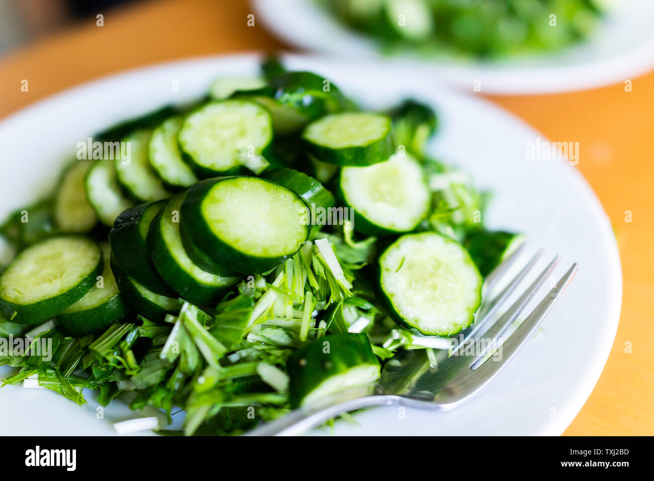 Home or restaurant with table and green salad dish closeup with Japanese cucumbers and mizuna greens Stock Photo