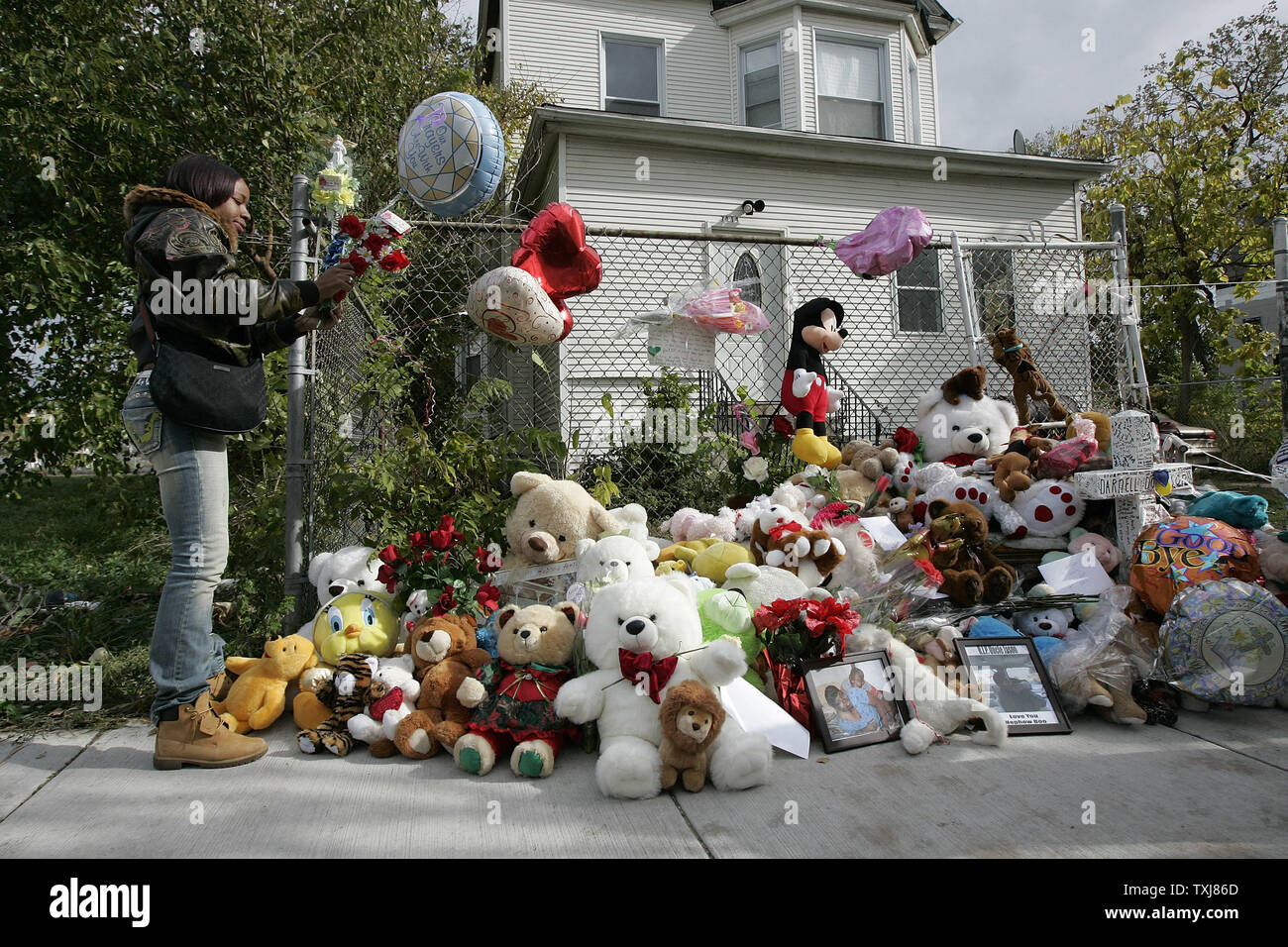 Necey Reed leaves a cross at a makeshift memorial in front