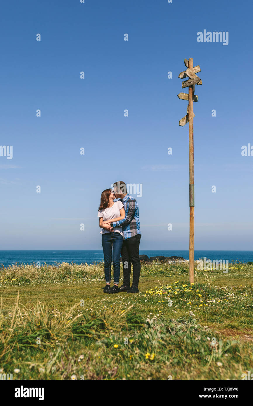 Couple kissing embraced by a direction sign Stock Photo