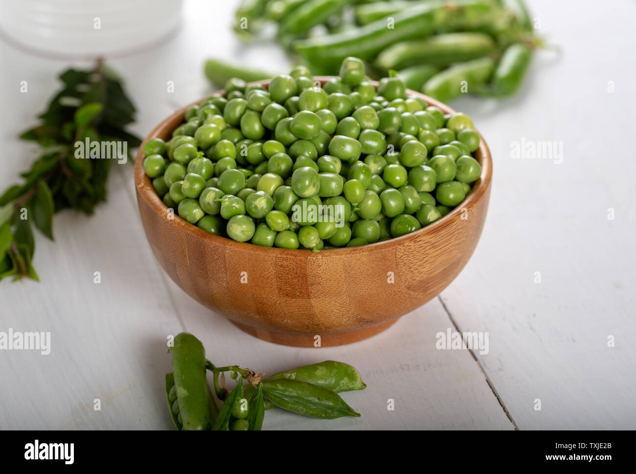 Fresh green peas in wooden bowl on white background. Stock Photo