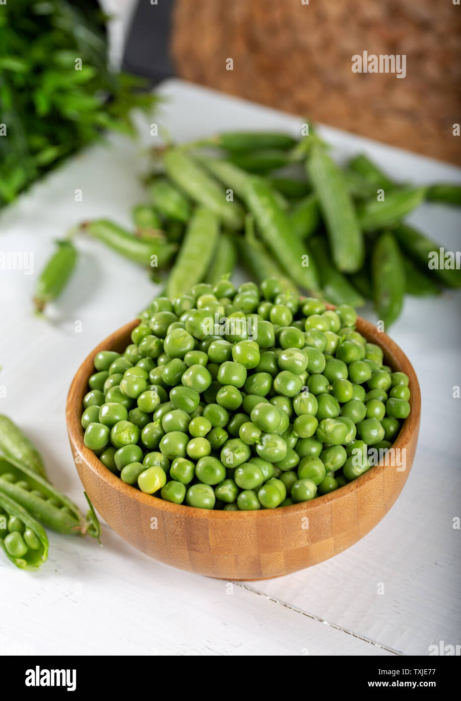 Fresh green peas in wooden bowl on white background. Stock Photo