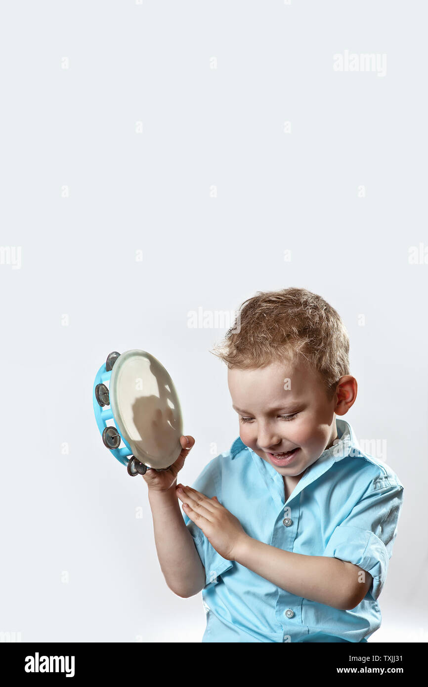 cheerful boy in a blue shirt holding a tambourine and smiling on a ...