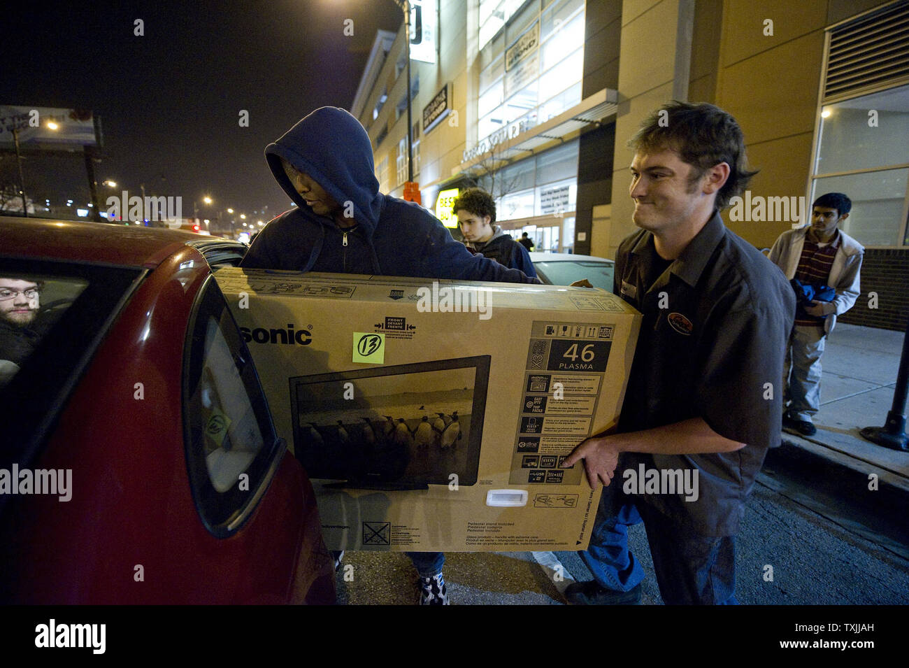 Best Buy employee Mike Markham (R) helps Lokesh Anand load his new television set into his car on 'Black Friday' on November 25, 2011 in Chicago. Best Buy along with Target and other retailers opened their stores at 12 a.m. or even Thursday night for the first time in years hoping to get an early start on 'Black Friday', the traditional start of the holiday shopping season. Stock Photo