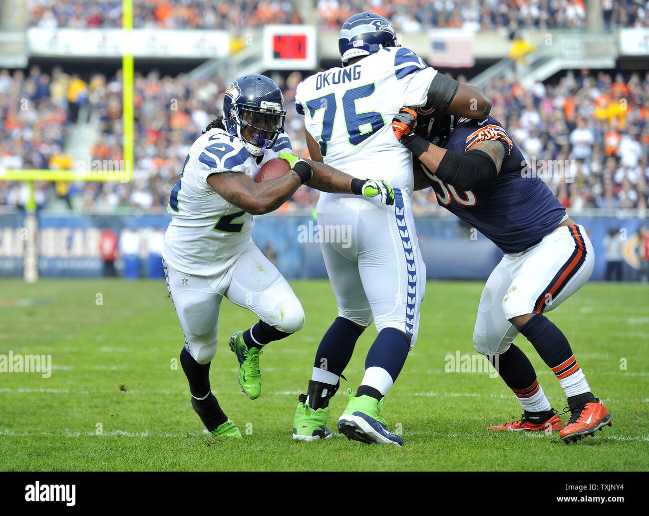 Seattle Seahawks tackle Russell Okung (C) blocks Chicago Bears defensive  end Julius Peppers (R) as running back Marshawn Lynch heads towards the end  zone on a 4-yard touchdown run during the second