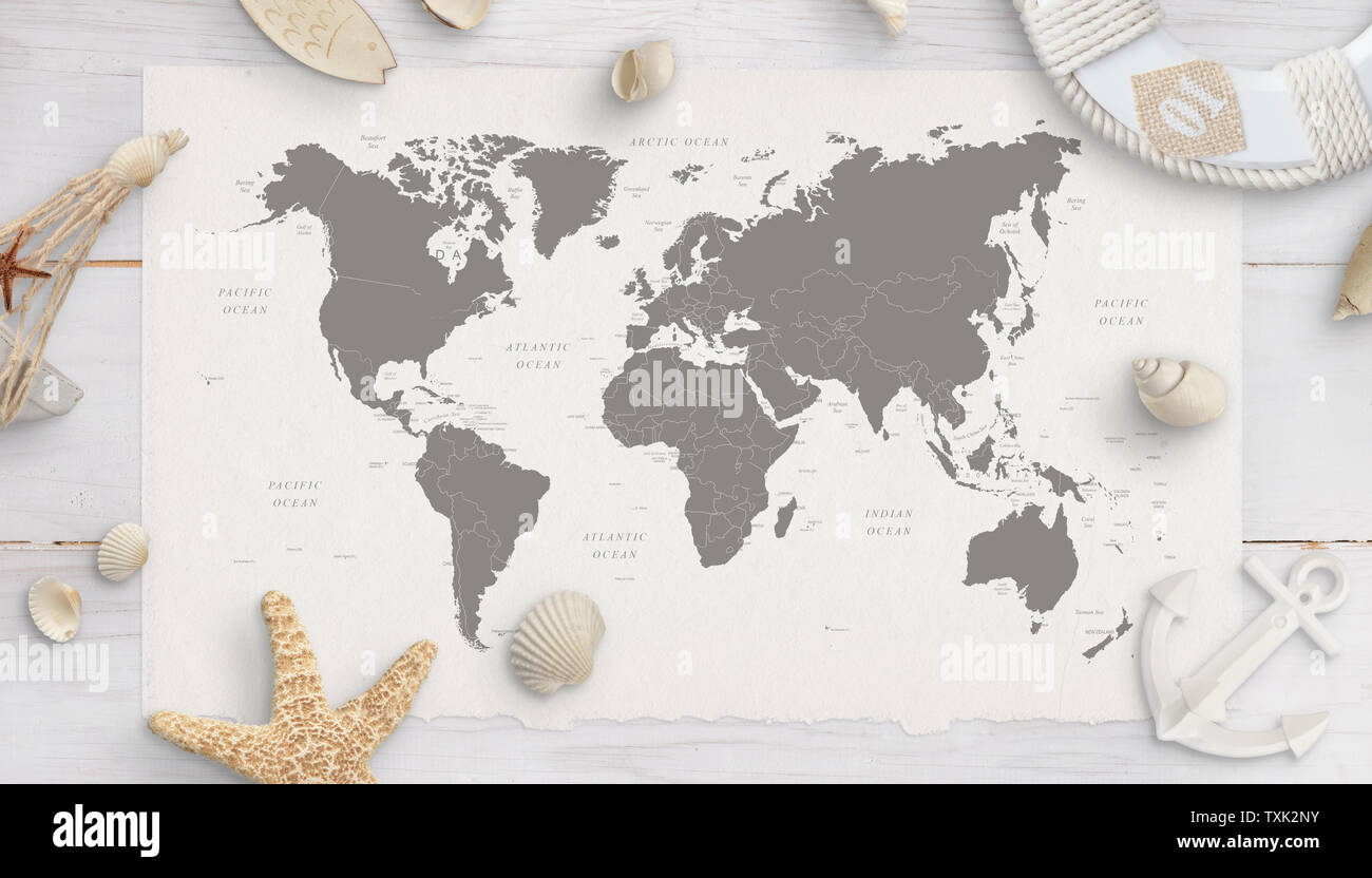 World map surrounded by shells, starfish, lifebelt, anchor. White wooden table in background. Flat lay, top view. Stock Photo