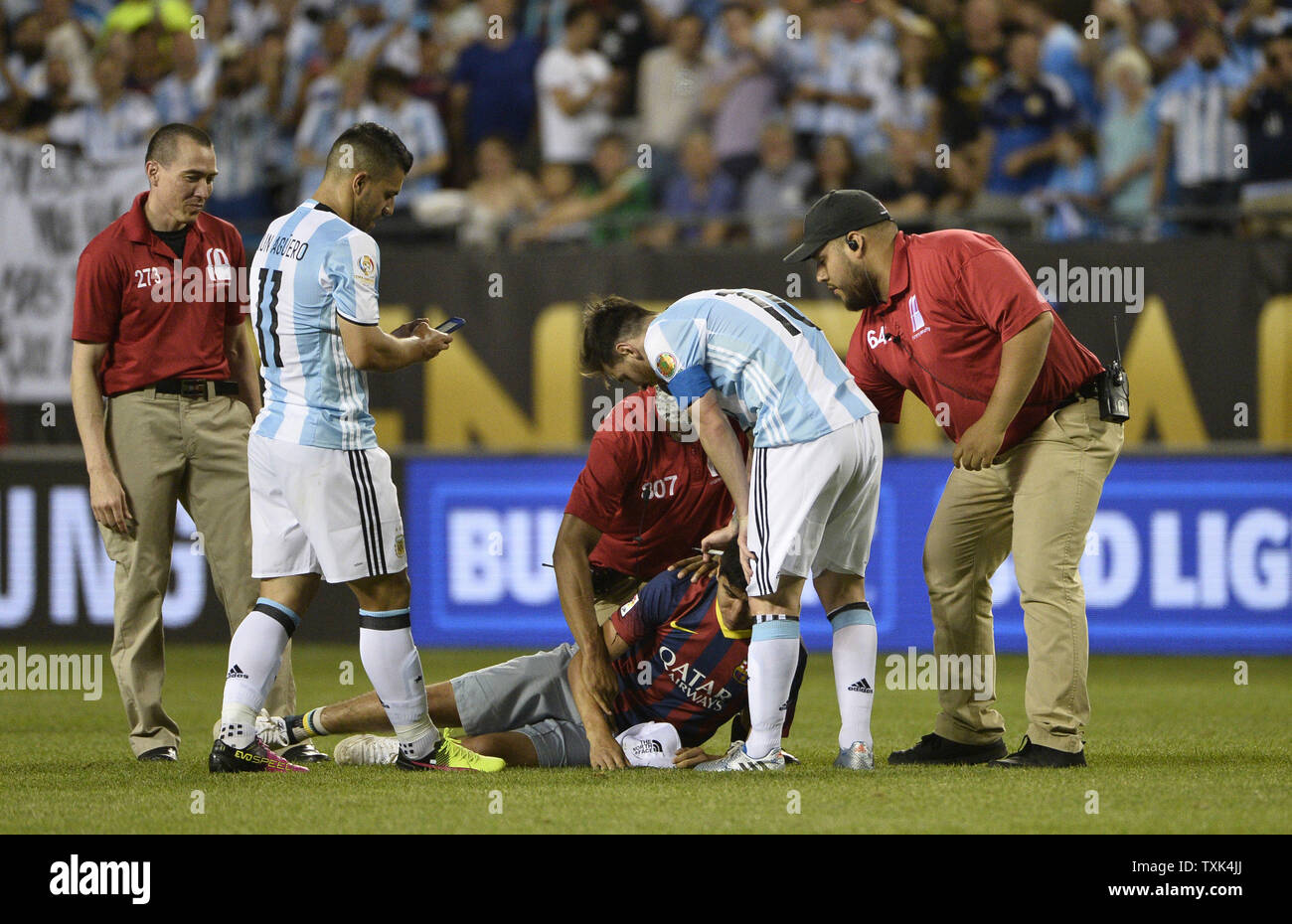 Argentina midfielder Lionel Messi (R) checks on a fan who rushed the field and was tackled by security as forward Sergio Aguero retrieve's the fan's phone after a 2016 Copa America Centenario Group D match against Panama at Soldier Field in Chicago on June 10, 2016. Argentina defeated Panama 5-0.     Photo by Brian Kersey/UPI Stock Photo