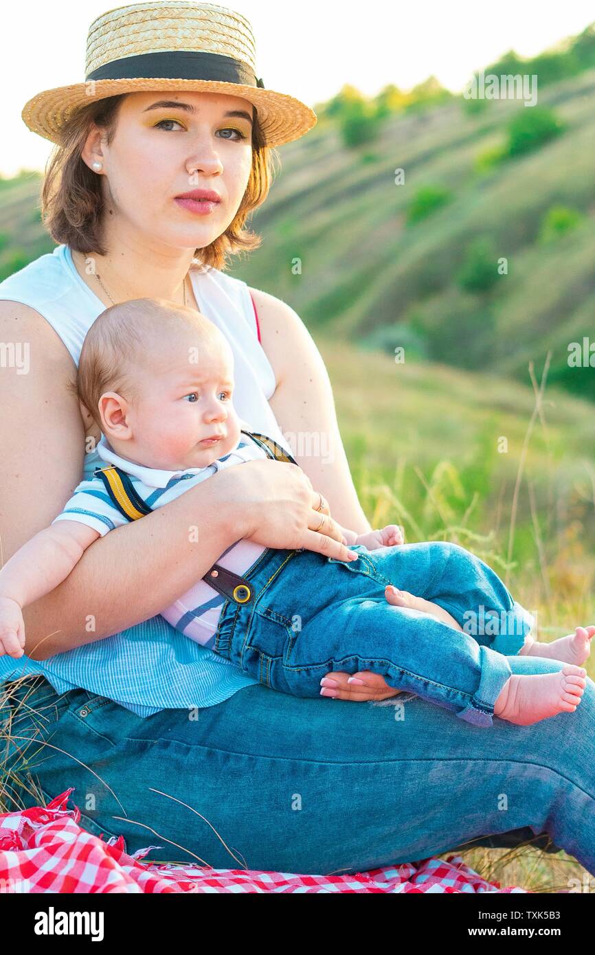 Mom with baby spending time together at sunset, on summer or autumn day, warm sunlight Stock Photo
