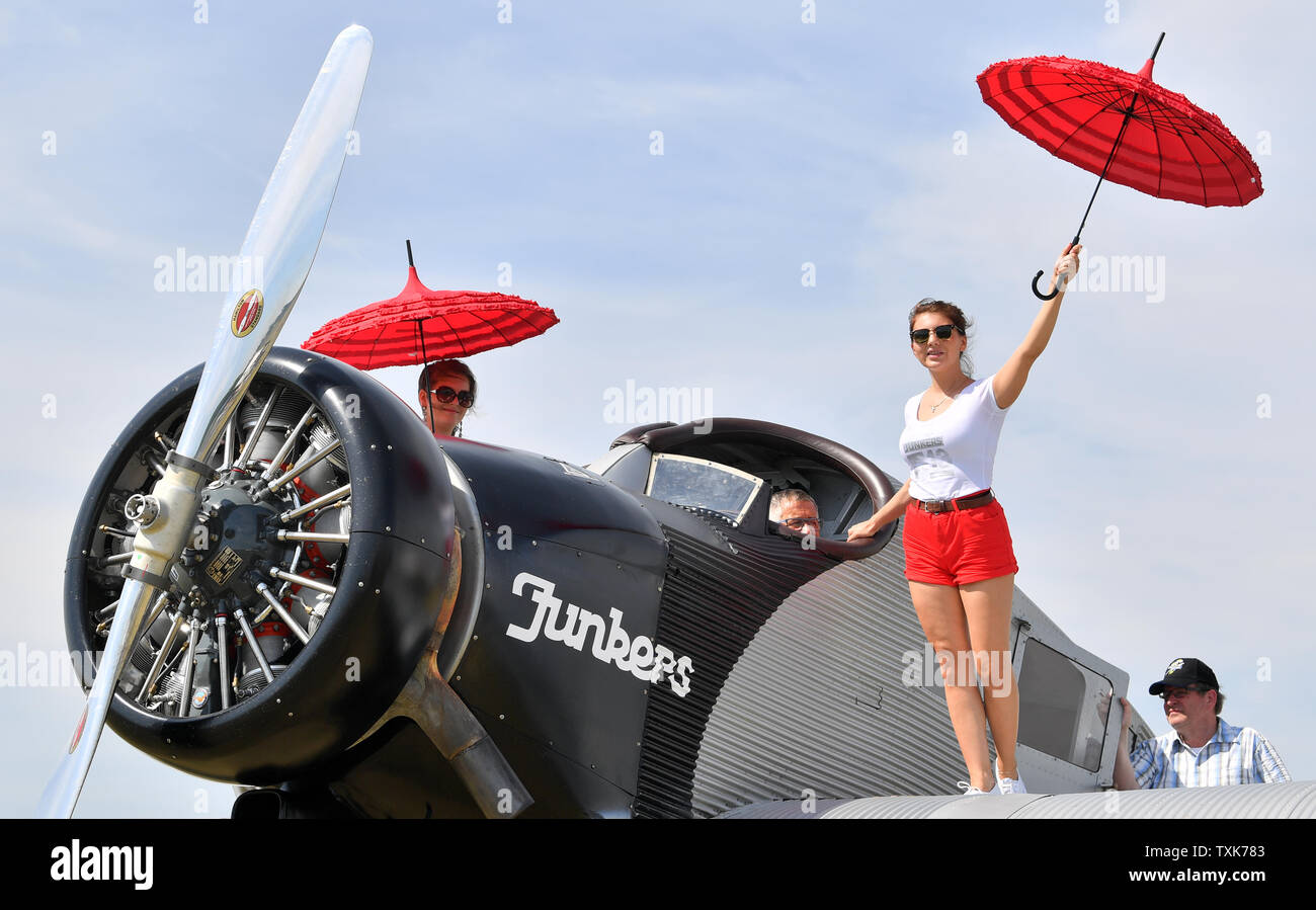 25 June 2019, Saxony-Anhalt, Dessau-Roßlau: The pilots in the cockpit of a Junkers F 13 at the airfield in Dessau are protected from the sun by hostesses with an umbrella. Exactly 100 years ago, an aircraft of this type took off for the first time in Dessau. The aircraft, designed by aircraft pioneer Hugo Junkers, was the world's first all-metal commercial aircraft and is regarded as a pioneer in civil aviation. Since 2016, the machine has again been manufactured in small series in Switzerland. Photo: Hendrik Schmidt/dpa-Zentralbild/dpa Stock Photo