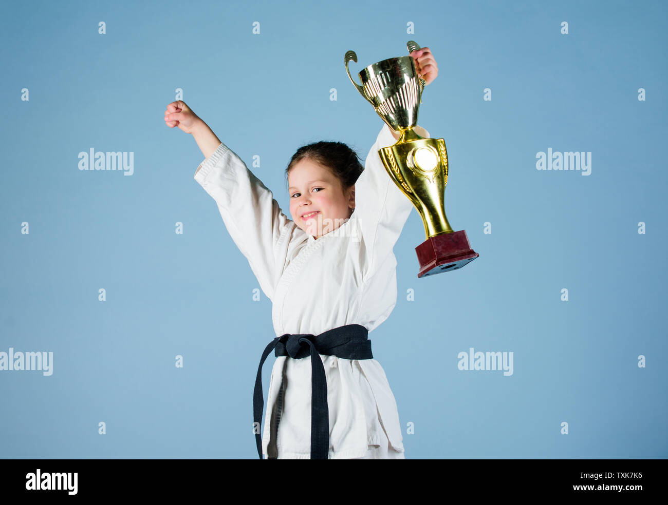 sport success. Training to be the best. small girl with champion cup.  martial arts. practicing Kung Fu. happy childhood. winner little girl in gi  sportswear. knockout. energy and activity for kids Stock