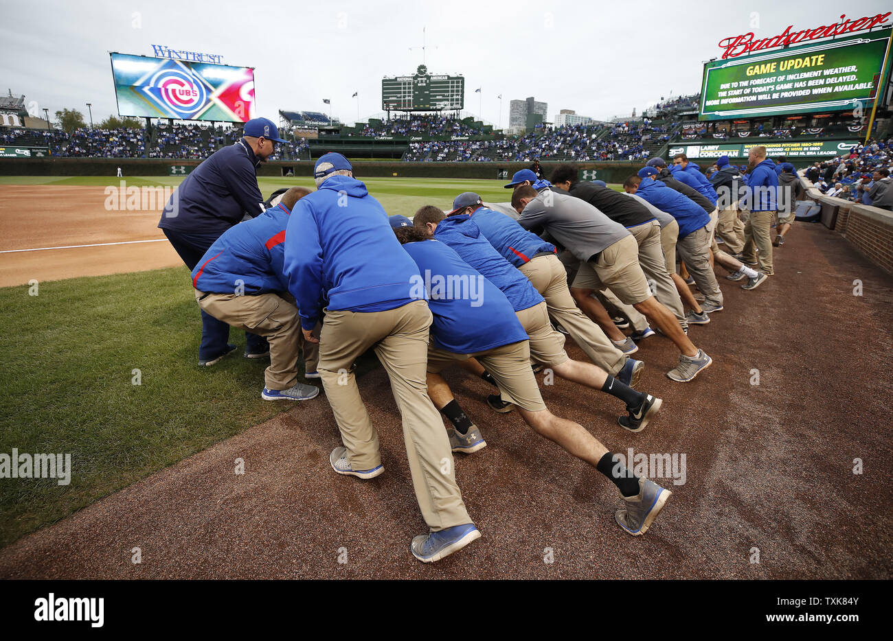 Chicago Cubs ground crew members cover the field during a weather delay