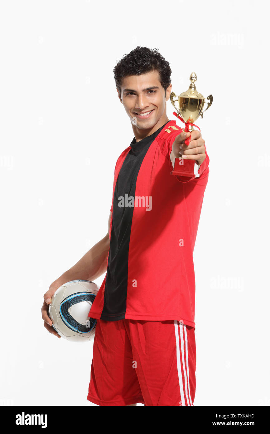 Portrait of a man holding a soccer ball and showing trophy Stock Photo ...
