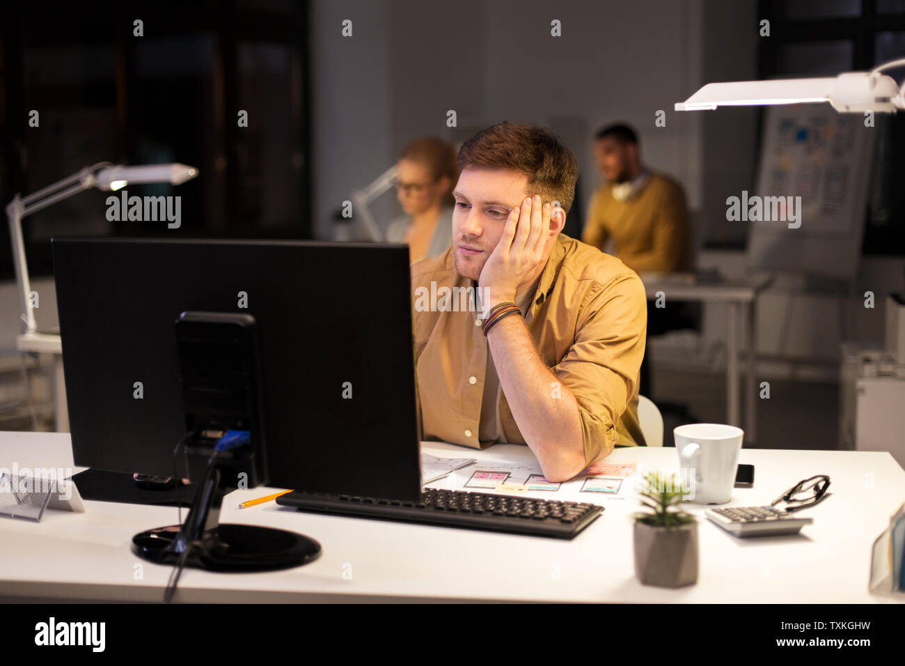 tired or bored man with computer at night office Stock Photo