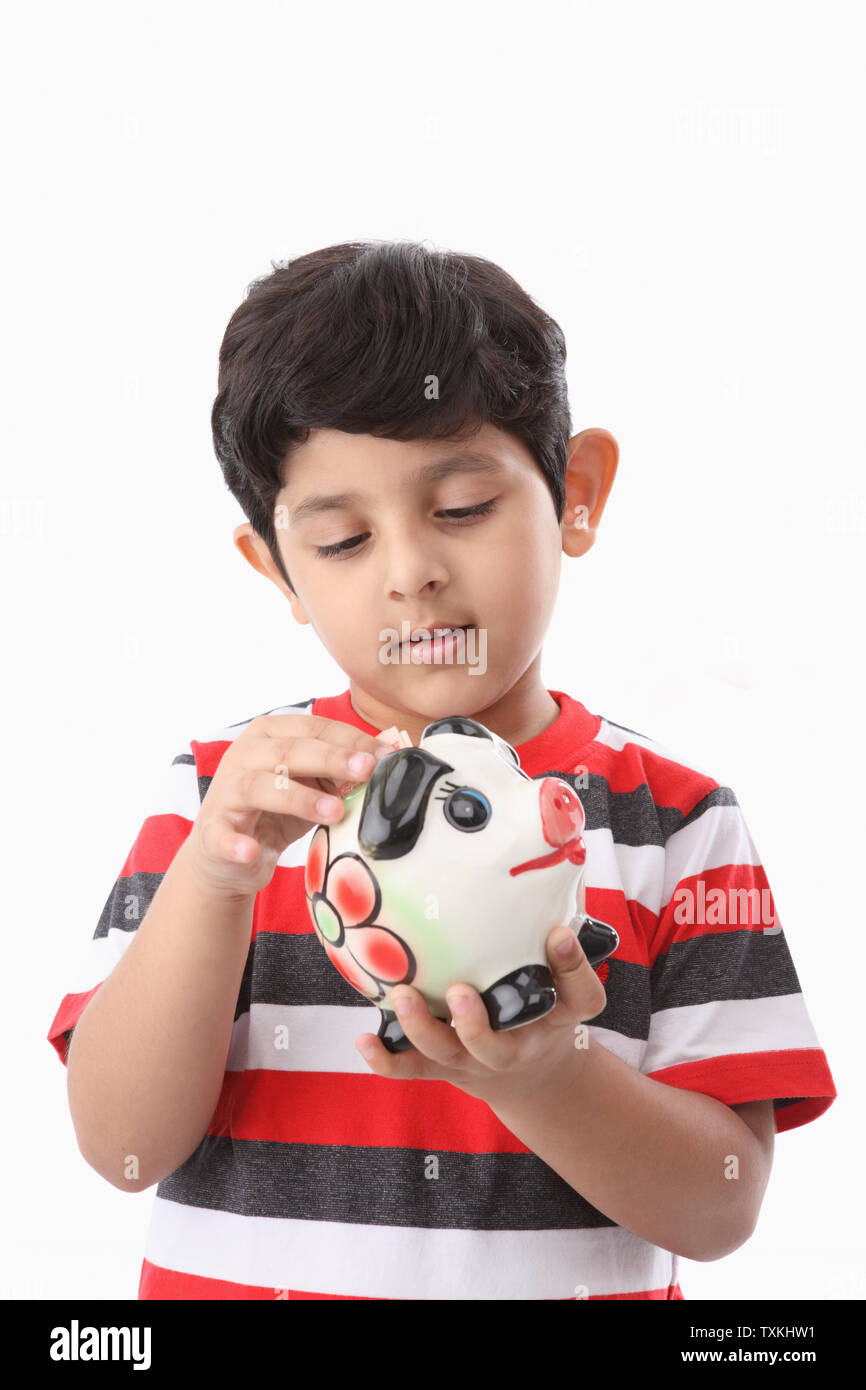 Boy putting banknote into a piggy bank Stock Photo - Alamy