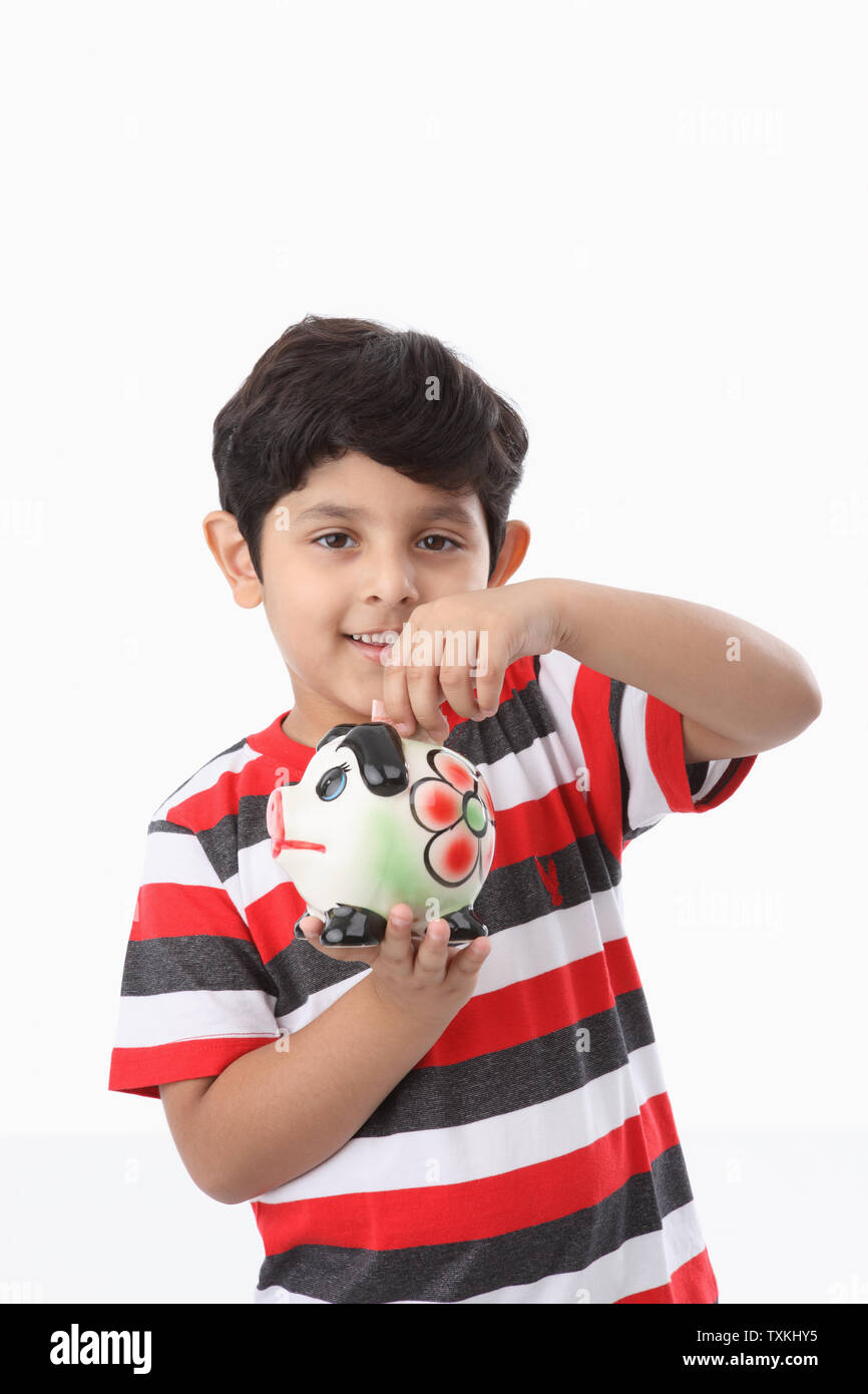 Boy putting banknote into a piggy bank Stock Photo - Alamy