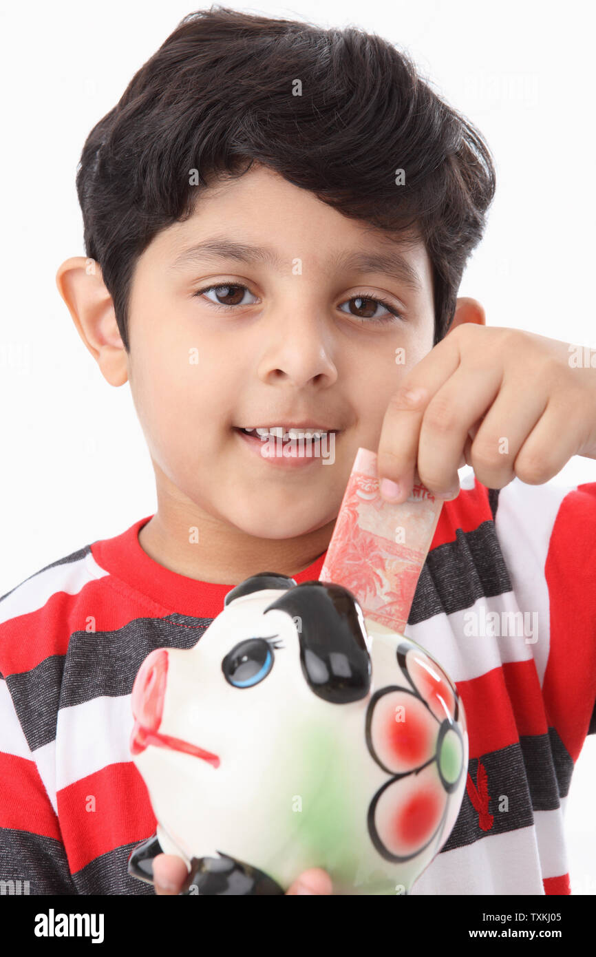 Boy putting banknote into a piggy bank Stock Photo - Alamy